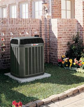 A green air conditioner sitting outside of a brick building.