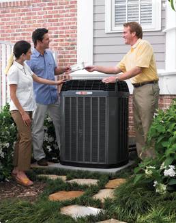 Three people are standing around a home with an air conditioner.