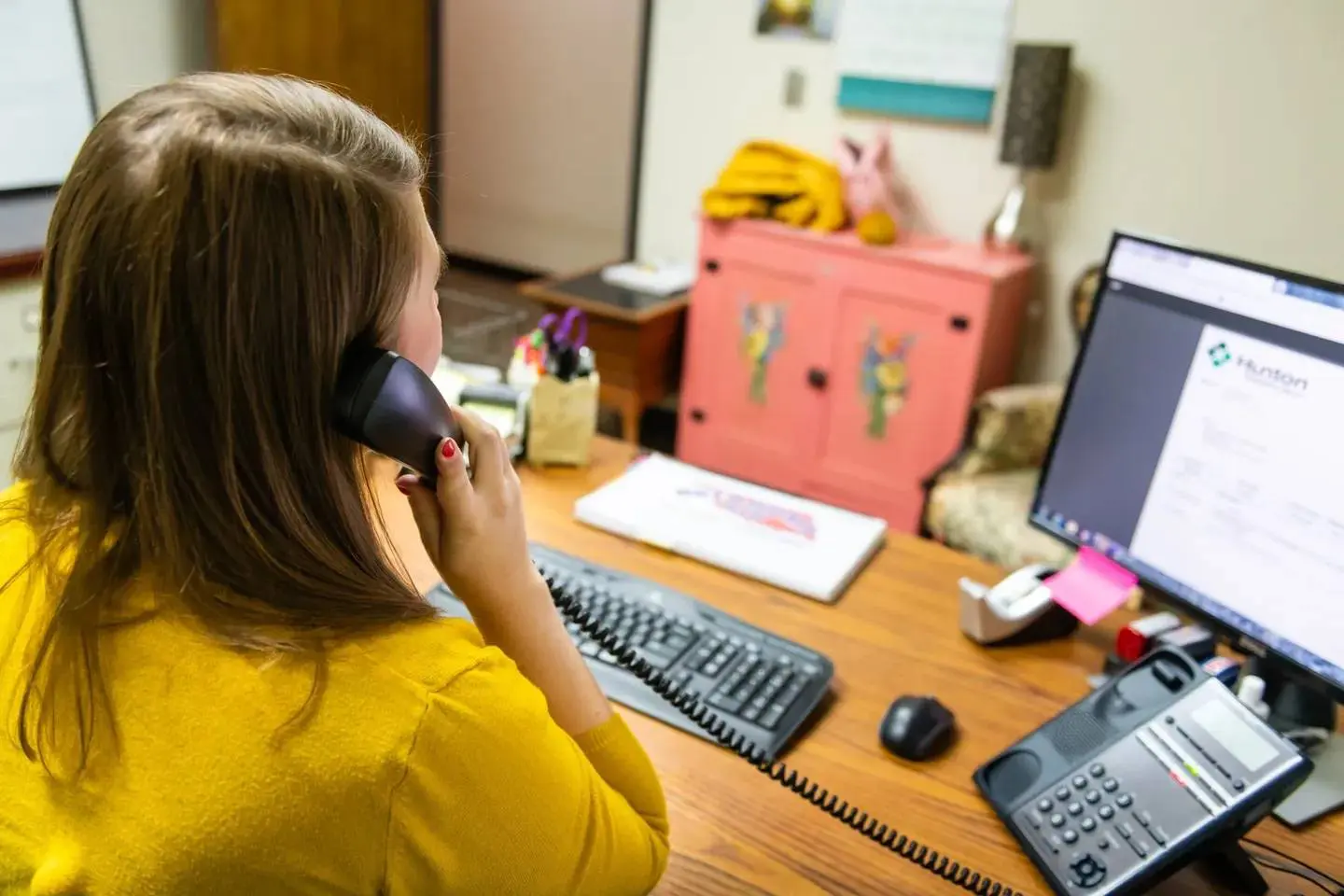 A woman sitting at her desk talking on the phone.